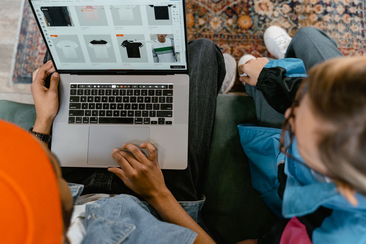 Two people looking through an online clothing shop on a laptop from above.